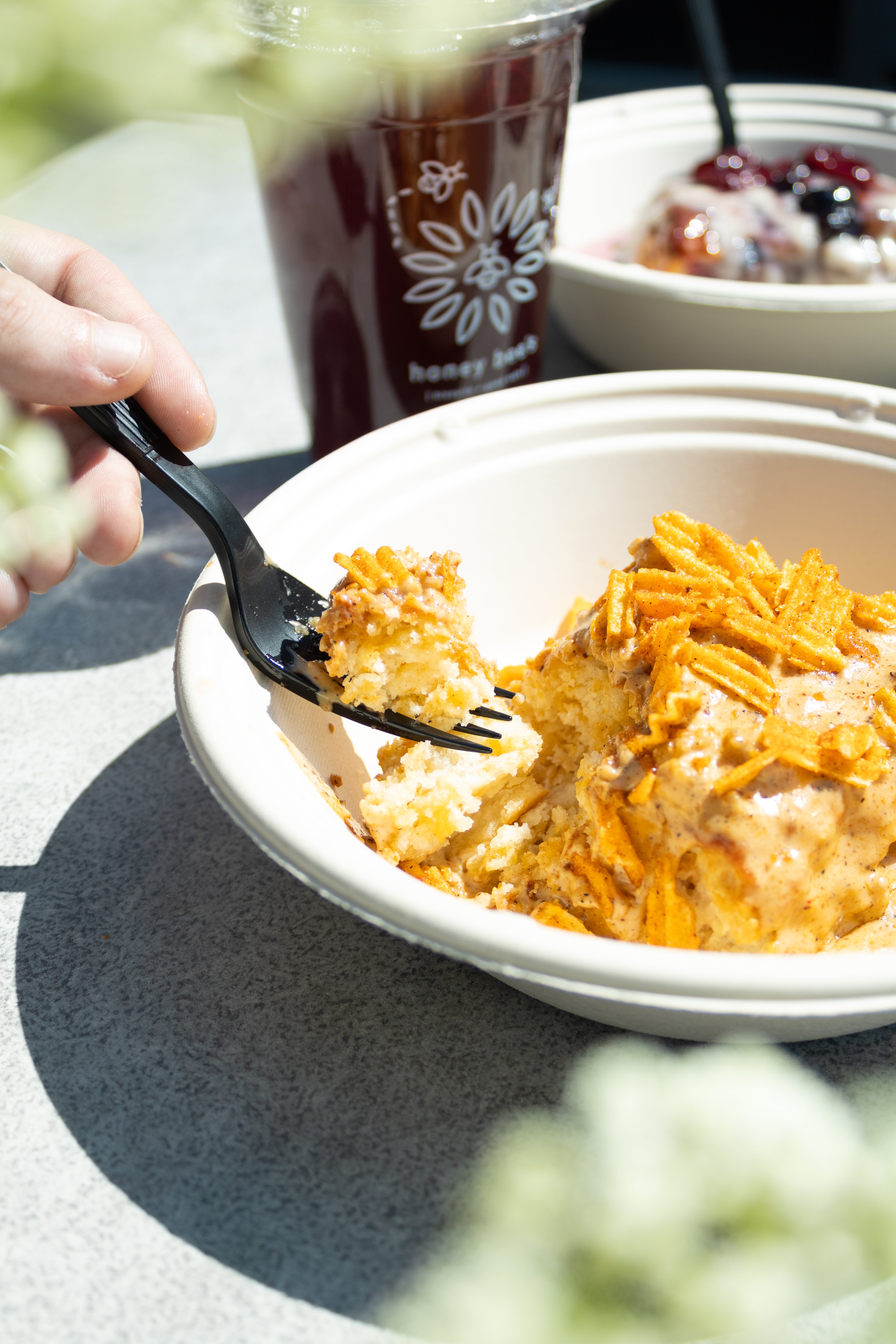 bowl of biscuits and gravy with a crunchy topping and a person grabbing a bite with a fork