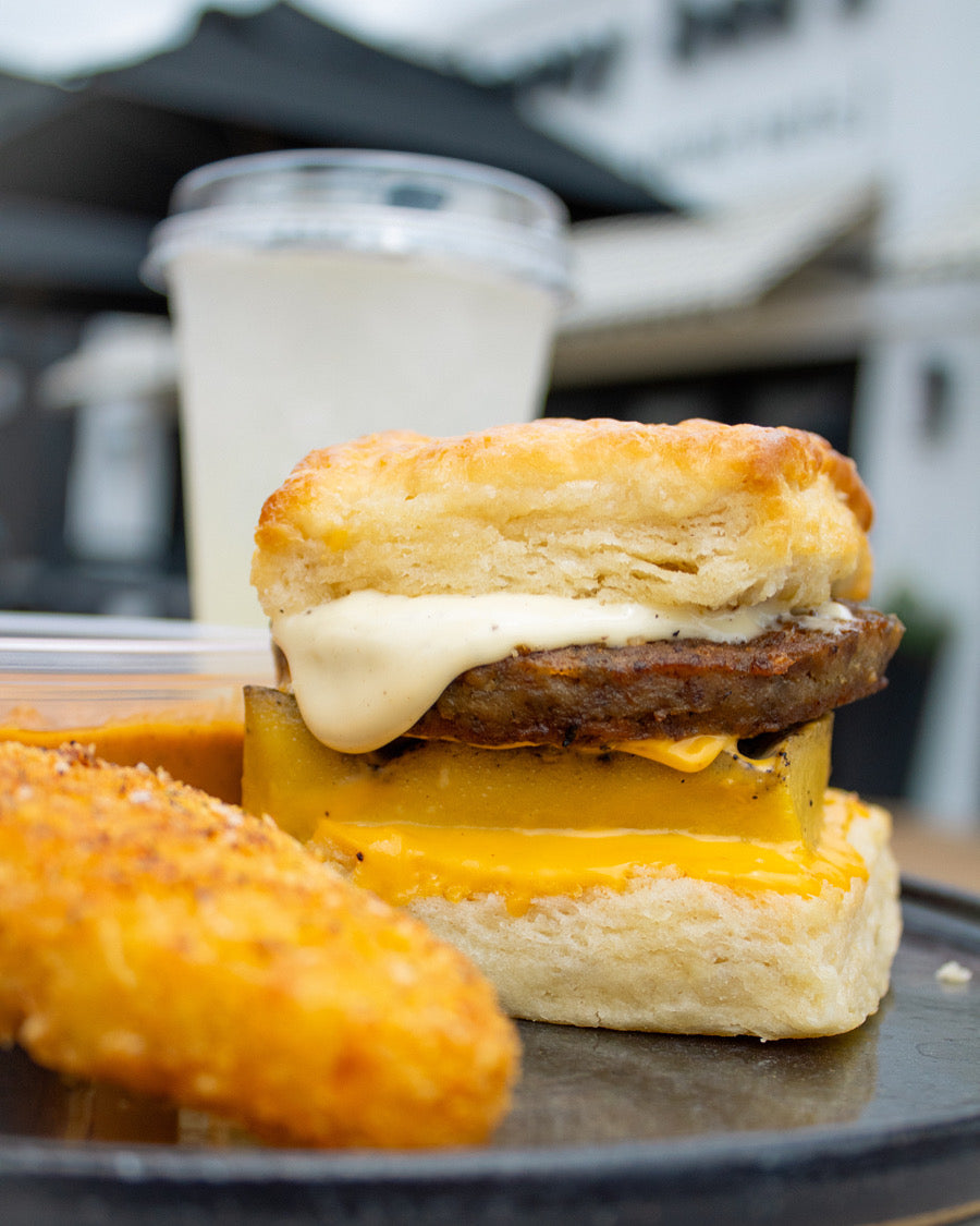 sausage, egg and cheese biscuit sandwich next to a hashbrown and glass of lemonade